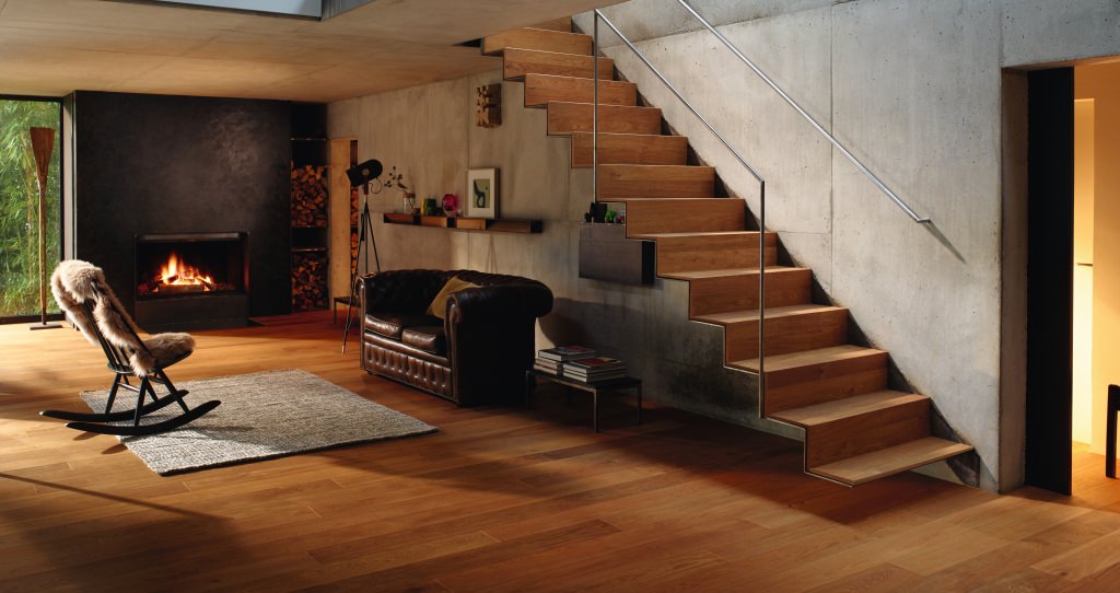 Modernes Wohnzimmer mit warmem HARO Parkettboden, der auch auf der Treppe verlegt ist.