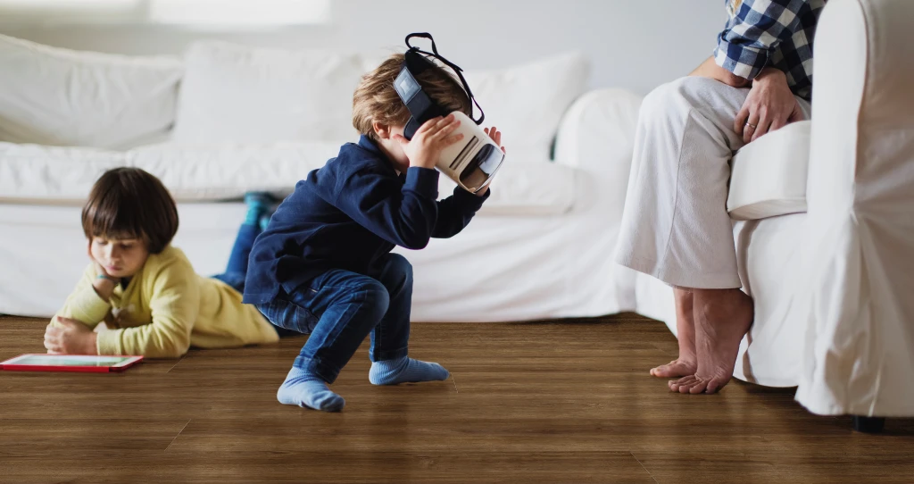 Due bambini giocano felicemente su un pavimento in laminato HARO scuro – una scena che unisce resistenza e comfort abitativo.
