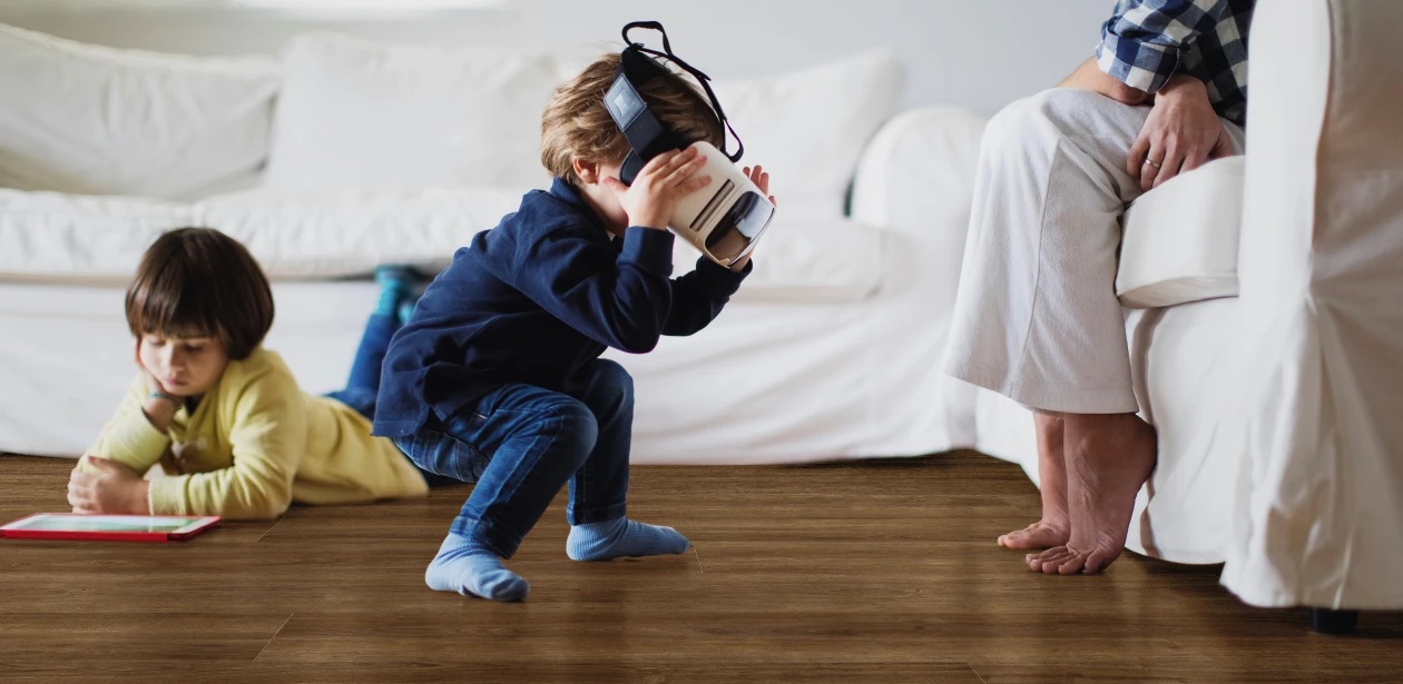 Due bambini giocano felicemente su un pavimento in laminato HARO scuro – una scena che unisce resistenza e comfort abitativo.