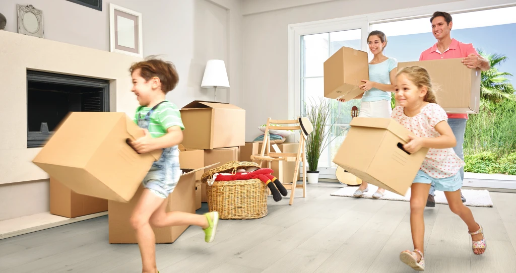 Eine Familie steht zwischen Umzugskartons in einer hellen Wohnung – der Moment eines Neuanfangs in den eigenen vier Wänden.