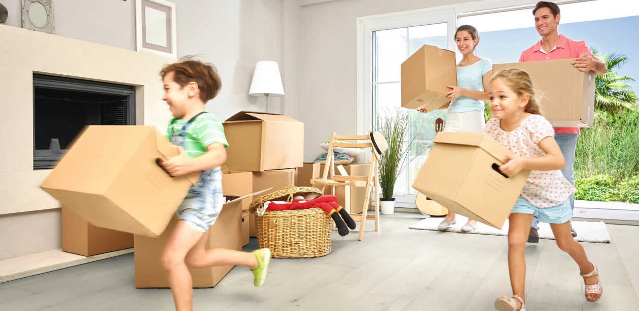 Eine Familie steht zwischen Umzugskartons in einer hellen Wohnung – der Moment eines Neuanfangs in den eigenen vier Wänden.