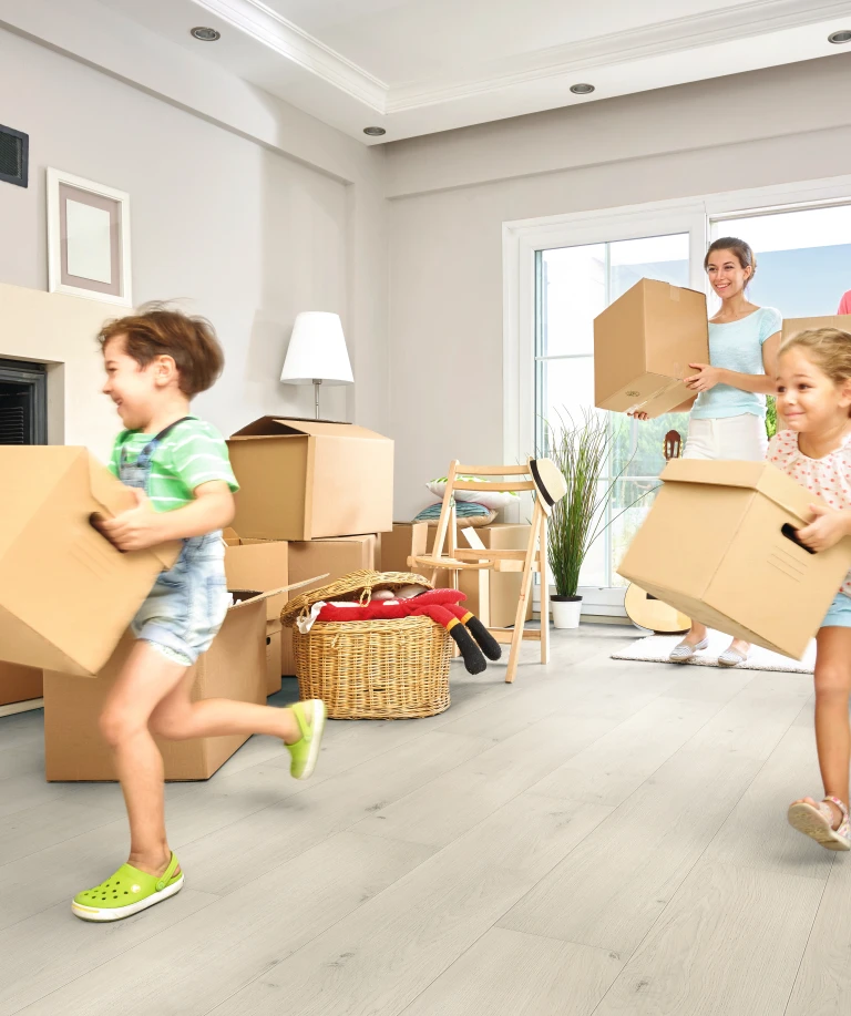 Eine Familie steht zwischen Umzugskartons in einer hellen Wohnung – der Moment eines Neuanfangs in den eigenen vier Wänden.