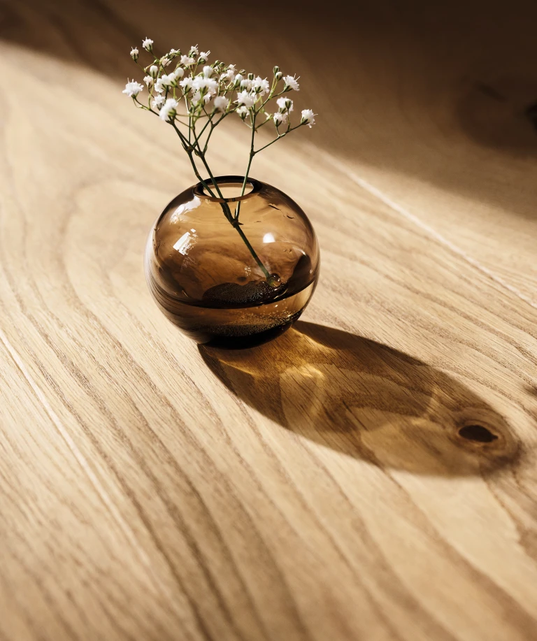 Elegant vase with a single branch, stylishly placed on a high-quality HARO parquet floor.