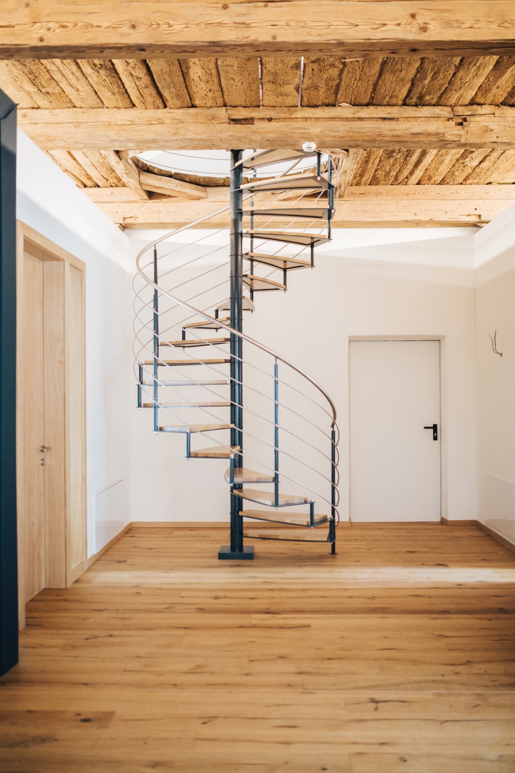 Plafond ancestral et sol neuf : l’escalier en colimaçon relie les deux univers avec finesse.