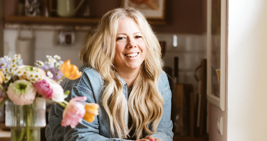 Die Influencerin Katharina Kammler steht mit einer Vase und einer Blume links neben ihr. Das elegante Arrangement unterstreicht eine stilvolle und harmonische Bildkomposition.