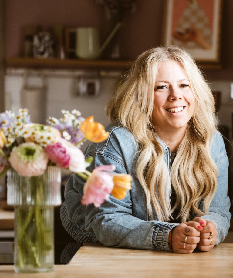 Die Influencerin Katharina Kammler steht mit einer Vase und einer Blume links neben ihr. Das elegante Arrangement unterstreicht eine stilvolle und harmonische Bildkomposition.