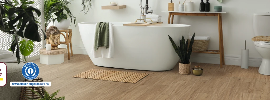 Modernes, hell eingerichtetes Badezimmer mit hellbraunem HARO Designboden; im Zentrum steht eine freistehende weiße Badewanne – zeitloses Ambiente mit wohngesunder Eleganz.