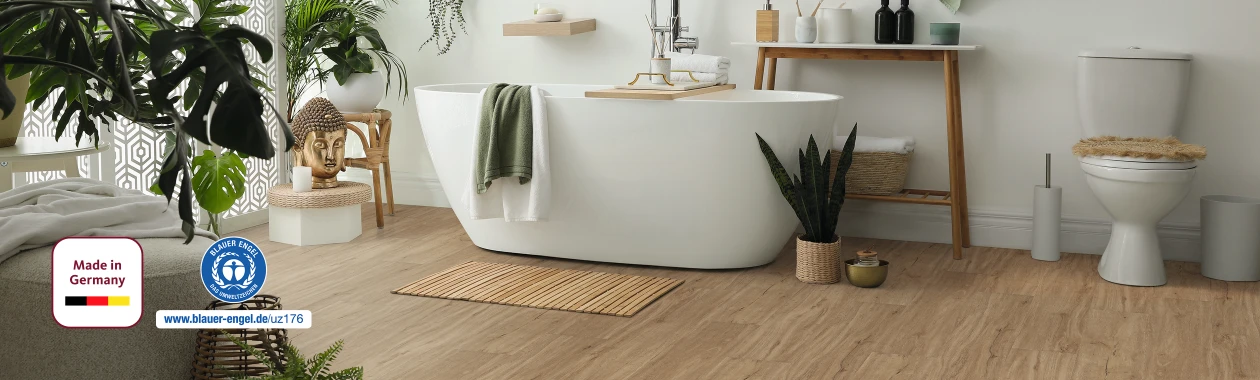 Modernes, hell eingerichtetes Badezimmer mit hellbraunem HARO Designboden; im Zentrum steht eine freistehende weiße Badewanne – zeitloses Ambiente mit wohngesunder Eleganz.