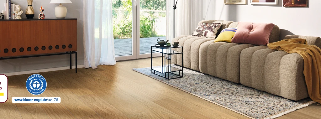 Cozy living room with a light brown HARO wood performance floor; furnished with a sofa and coffee table, bathed in natural daylight streaming generously from outside.