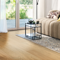 Acogedor salón con un suelo de madera HARO de alto rendimiento en tono marrón claro; amueblado con un sofá y una mesa de centro, bañado por luz natural que entra generosamente desde el exterior.