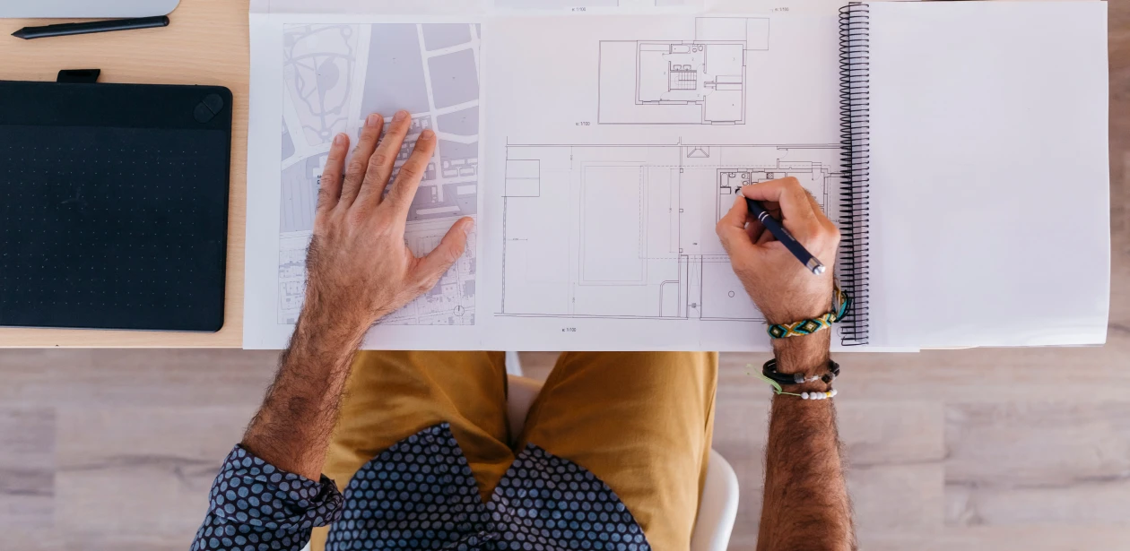 Mann zeichnet auf einem Raumplan – Planung und Berechnung von Bodenflächen.