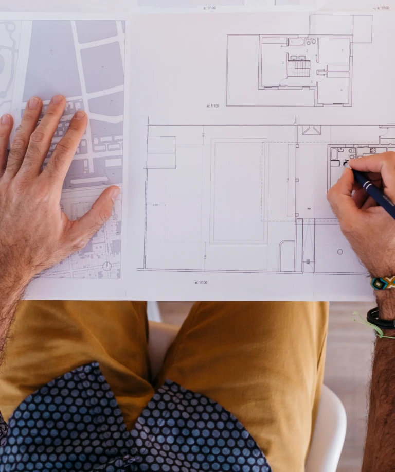 Mann zeichnet auf einem Raumplan – Planung und Berechnung von Bodenflächen.