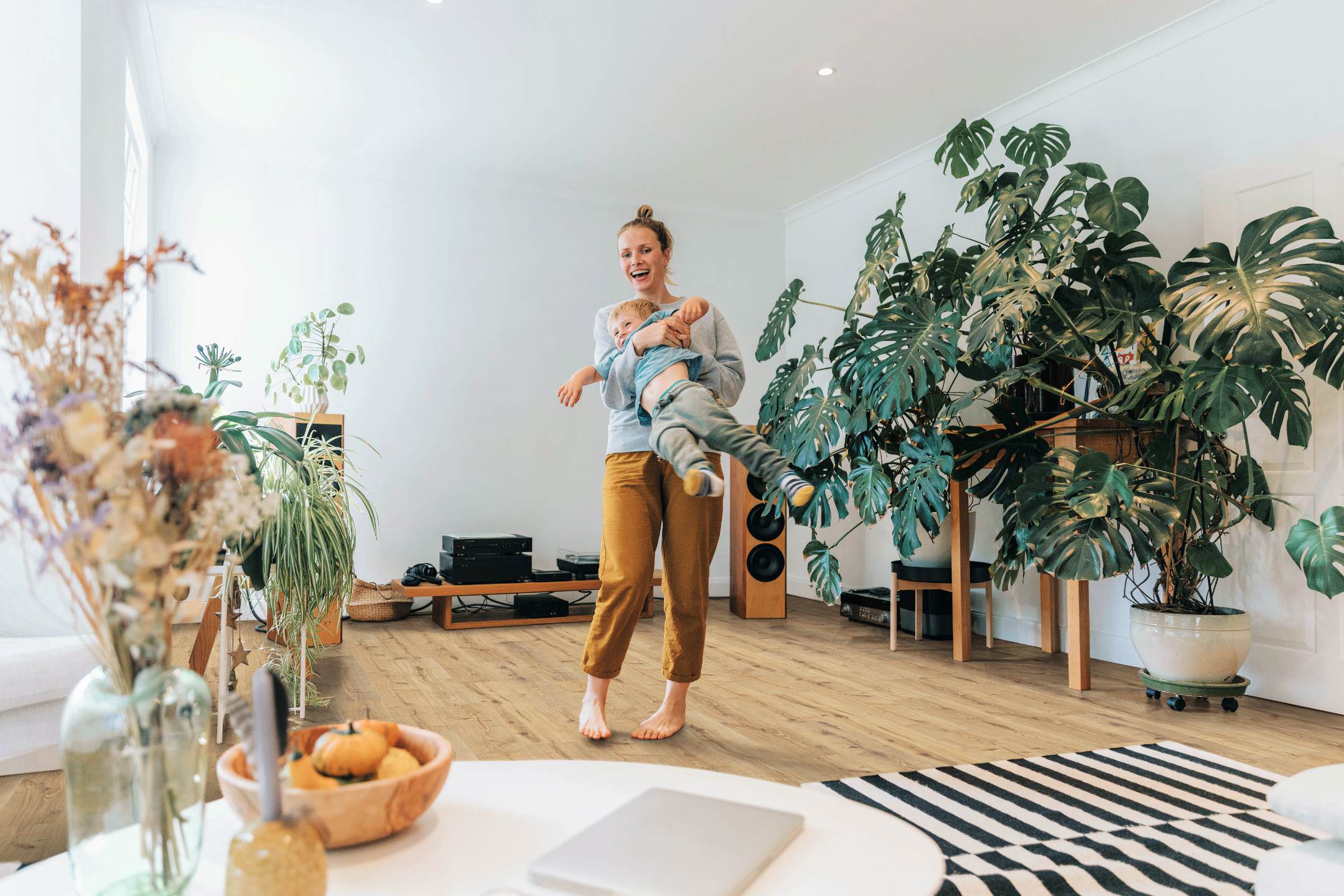 Salon ouvert avec un sol stratifié HARO clair. Au centre, une femme tient son fils dans ses bras, créant une ambiance chaleureuse.