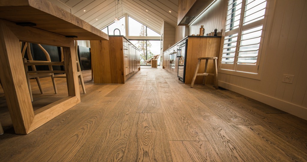 Die Parkettoberfläche bildet einen spannenden Kontrast zu den hell gestalteten Wänden und Decken des riesigen Wohn- und Küchenbereichs.