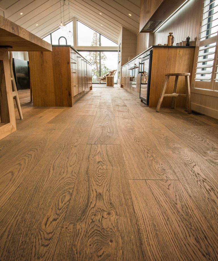 Die Parkettoberfläche bildet einen spannenden Kontrast zu den hell gestalteten Wänden und Decken des riesigen Wohn- und Küchenbereichs.