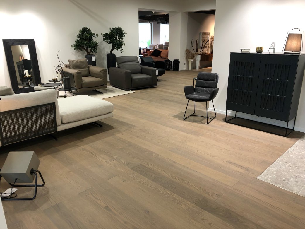 Die graue Anmutung des Parkettbodens bildet attraktive Kontraste mit den kräftigen Farben der Möbel und Sitzmöbel.