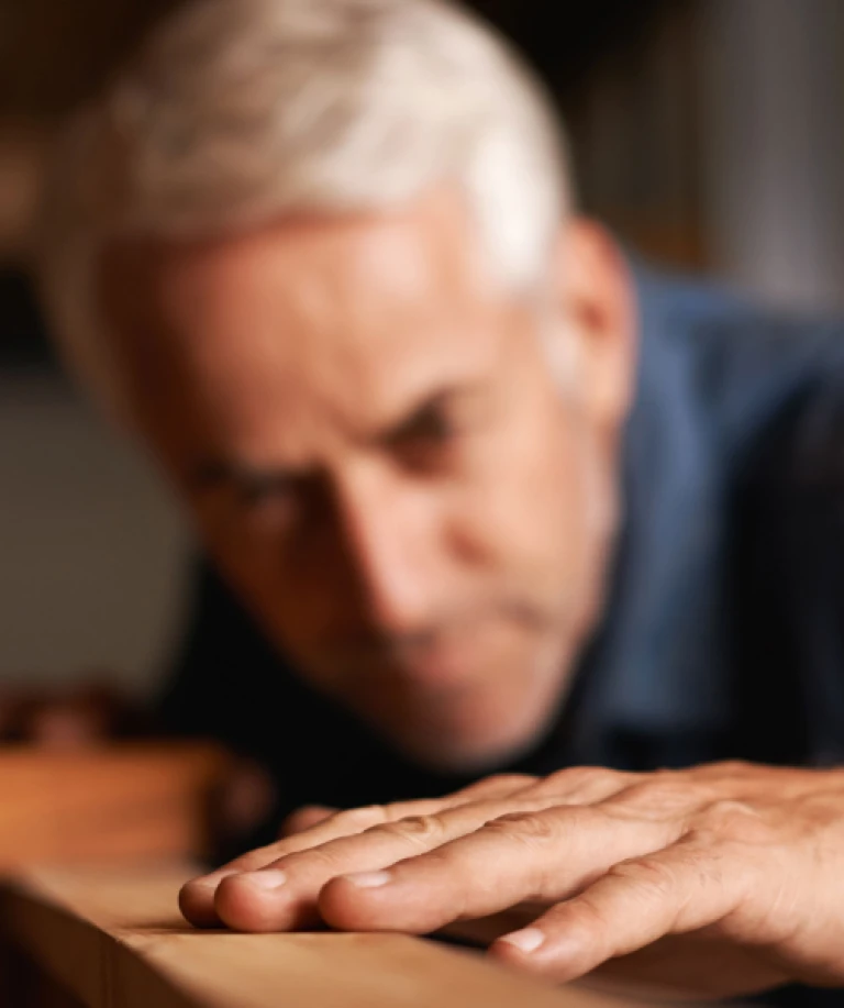 Ein Herr begutachtet konzentriert eine einzelne Diele – Ausdruck von Qualitätsbewusstsein, handwerklicher Präzision und dem Anspruch auf Perfektion im Detail.